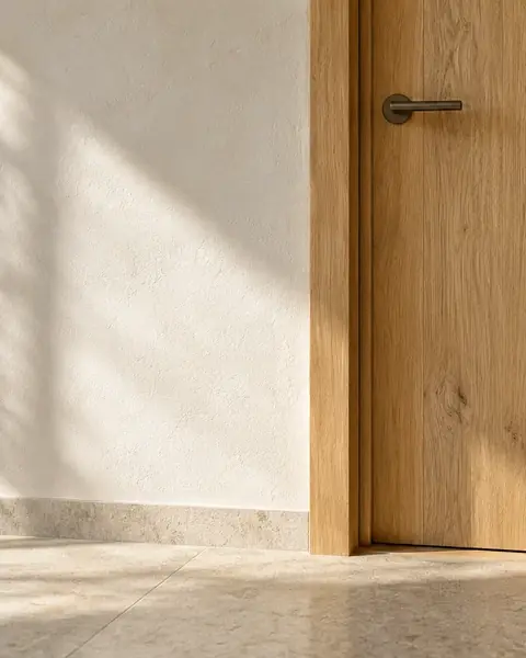 Detail einer Eichenholztür neben einer hellen Wand und Naturstein