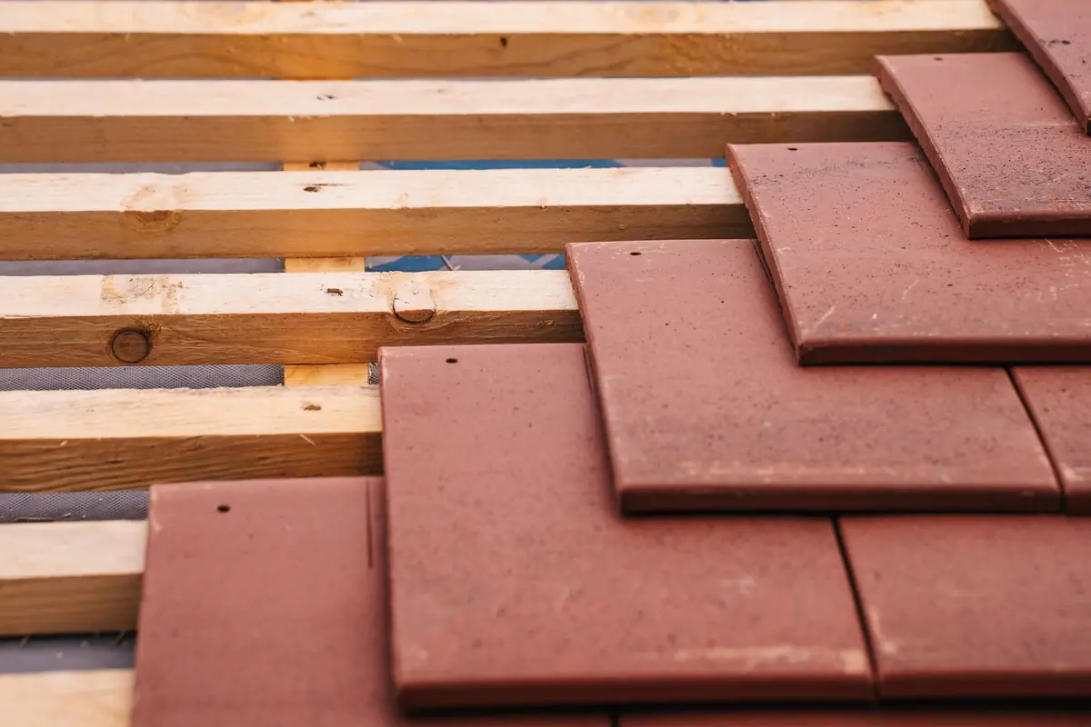 Rote Flachziegel auf frischer Holzlattung, ein Teil ist schon verlegt